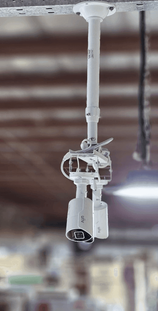 Twin Uniview bullet CCTV cameras pole-mounted on high warehouse ceiling in Kuwait